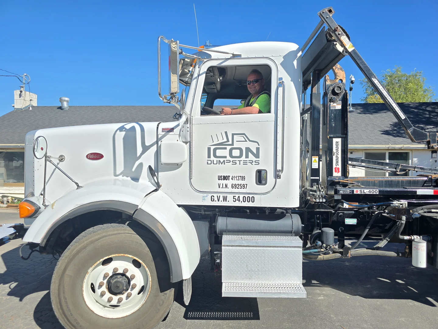 Icon Dumpsters local delivery driver in a branded roll-off truck